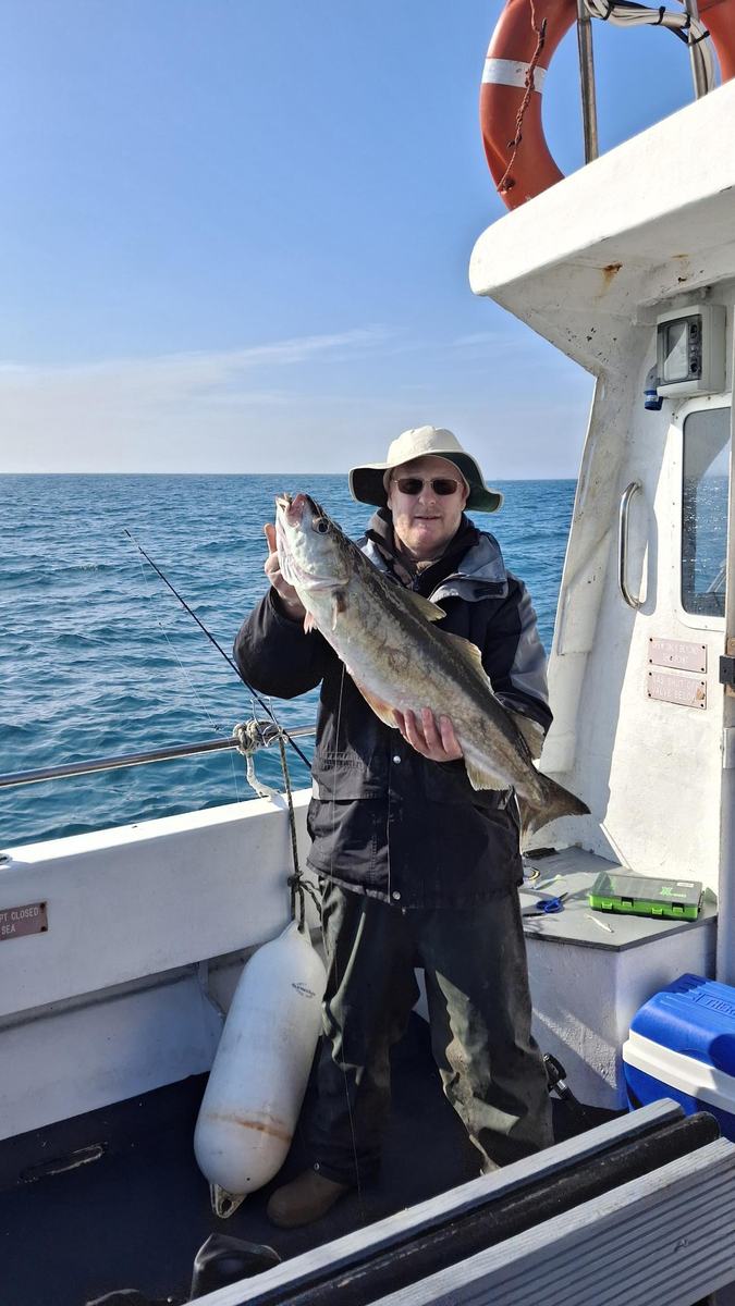 Angler with pollack aboard Lady of the Lake, life ring visible